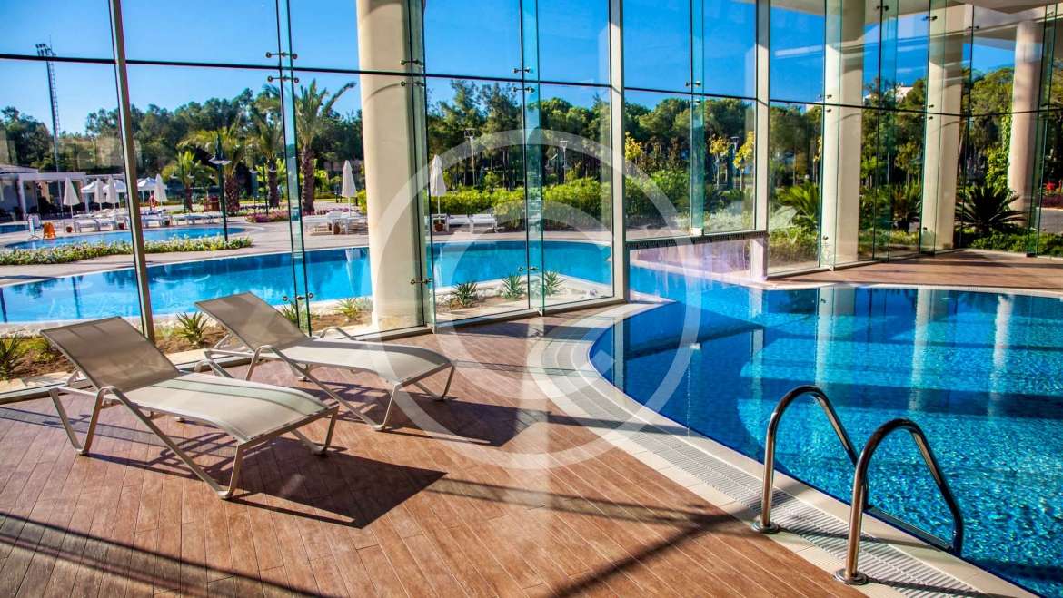 Freeform pool design using grass with cabana & waterfall